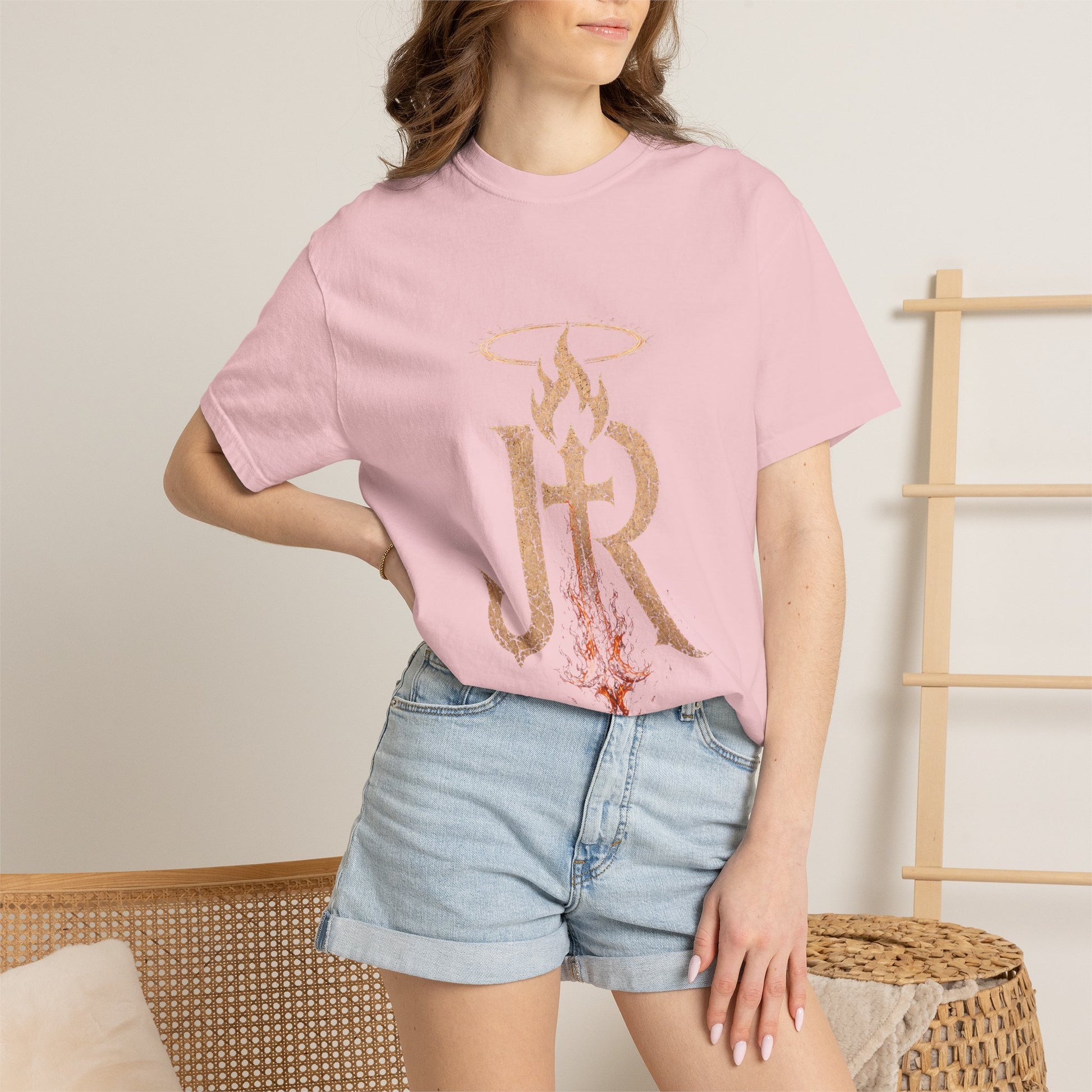 Person wearing a pink t-shirt with gold lettering and denim shorts on a neutral background