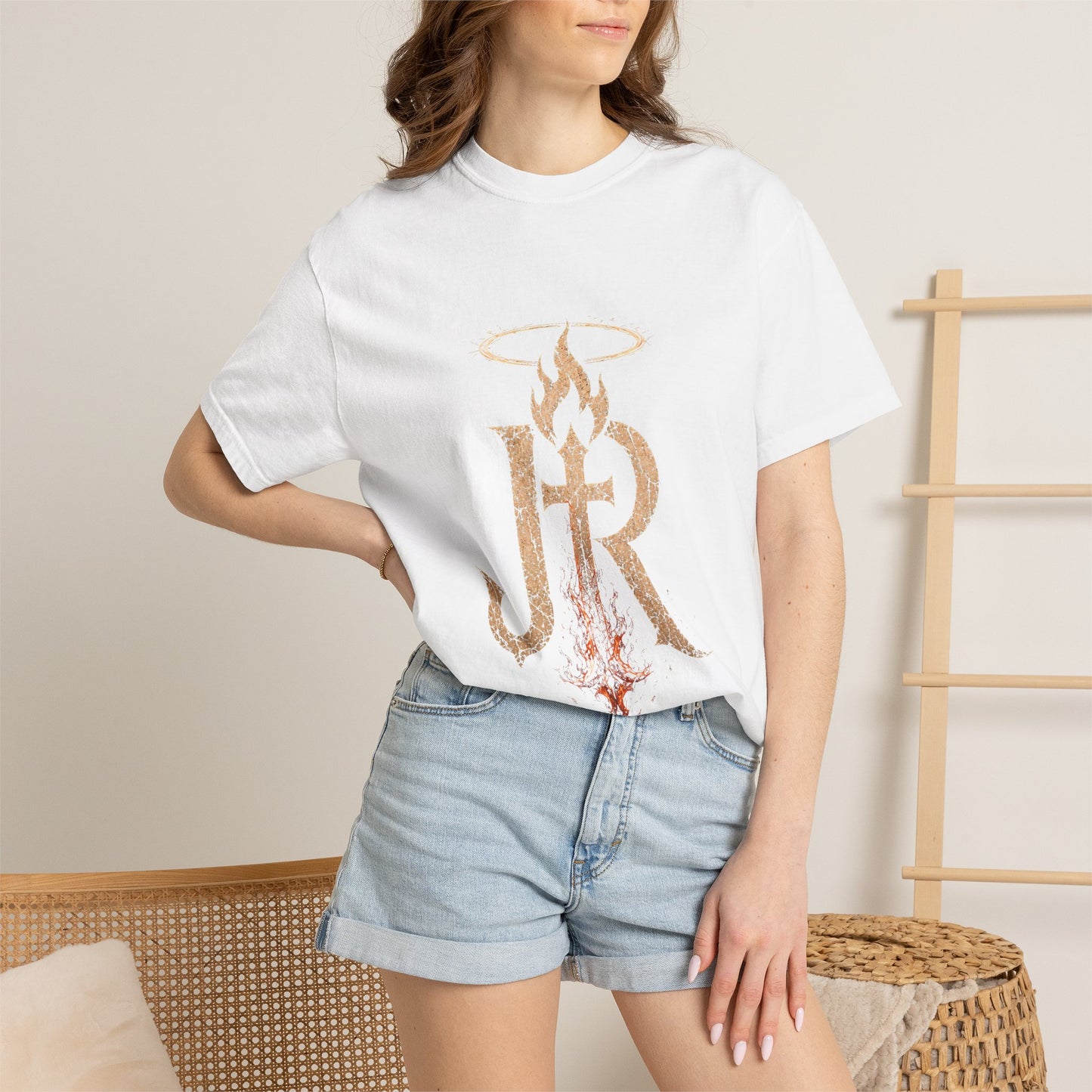 Person wearing a white t-shirt with a graphic design and denim shorts in a casual setting.