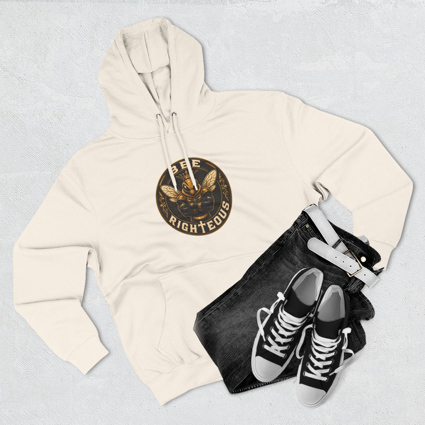 Beige hoodie with a logo, black jeans, and black sneakers on a light gray background
