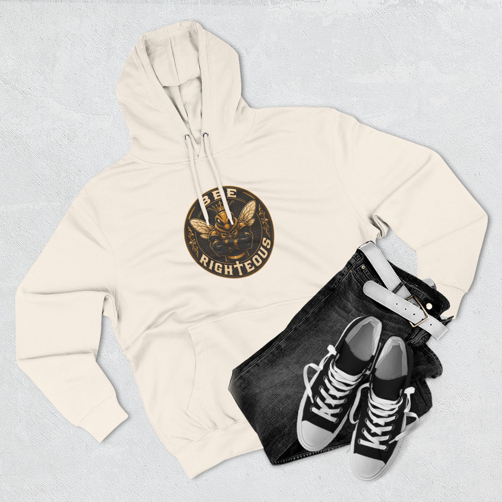 Beige hoodie with a logo, black jeans, and black sneakers on a light gray background