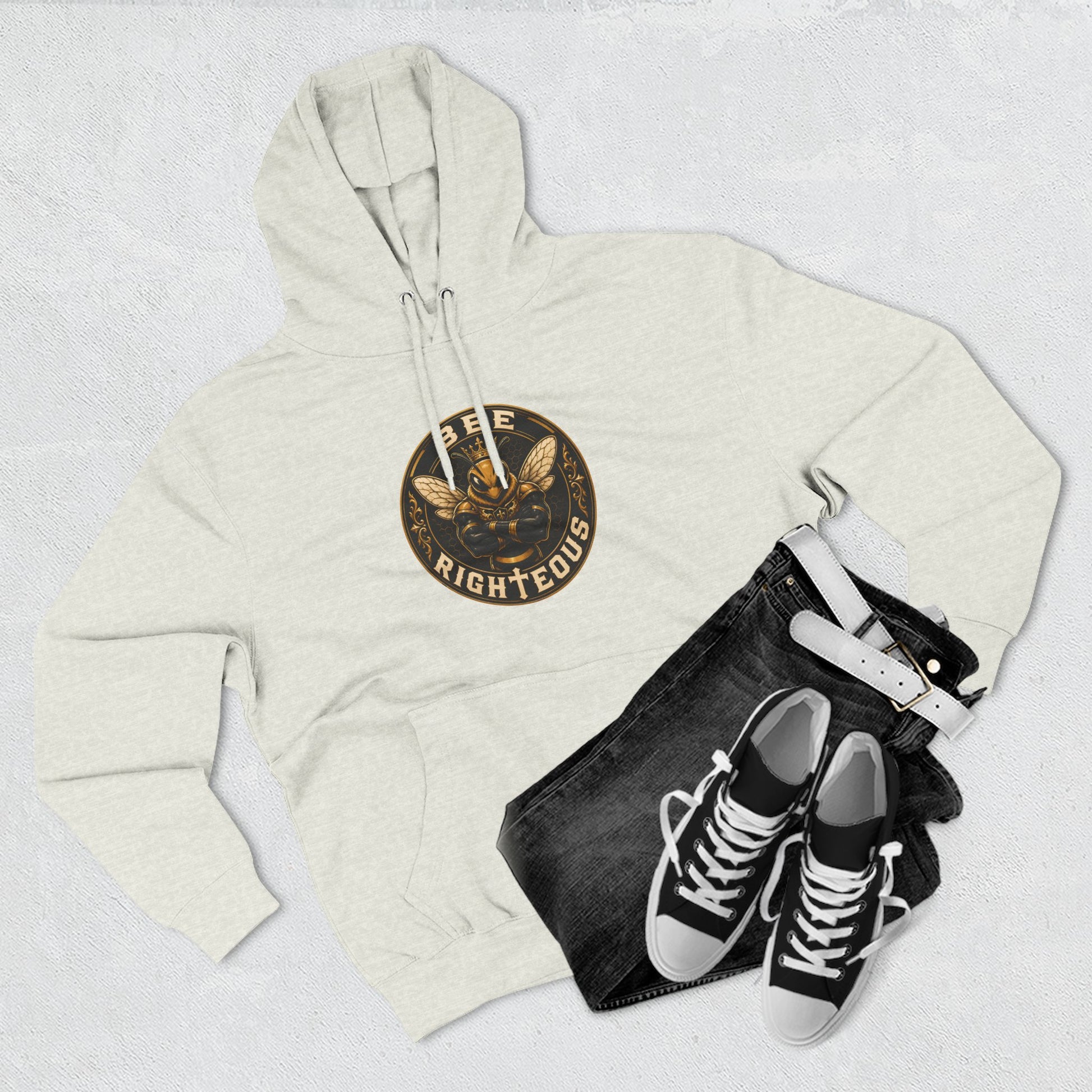 Beige hoodie with a logo, black jeans, and black sneakers on a light gray background